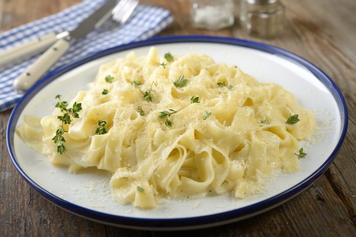 Fettuccine Alfredo with thyme on a rustic table
