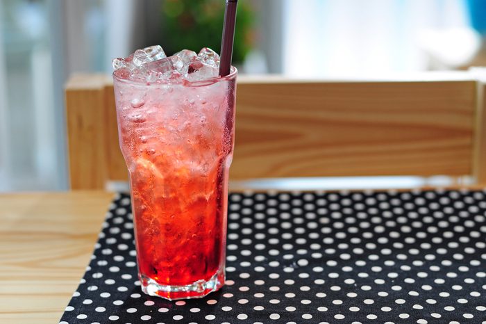 Strawberry italian soda on wood table with black polka dot tablecloth.