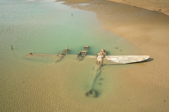 The wrech of a crashed WW2 P38 Lightning Aircraft laying on a beach in Wales, UK