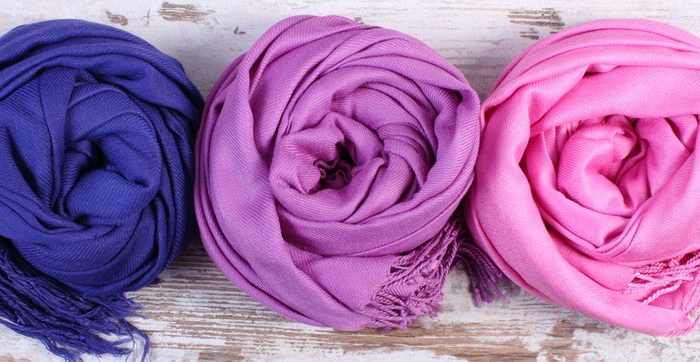 Colorful scarves on old rustic wooden background, womanly accessories, warm clothing for autumn or winter