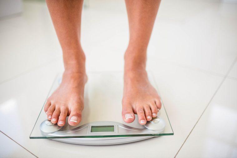 Feet of woman on weighting scale at home