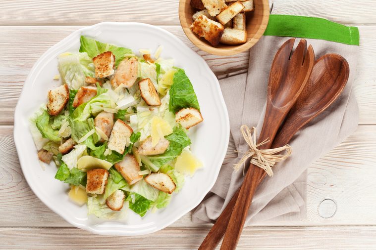 Fresh healthy caesar salad on wooden table. Top view