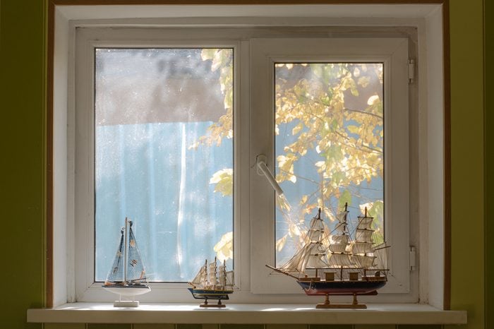 a window in the bedroom, a collection of ship models, a view of the street with trees