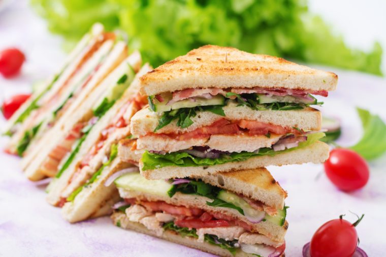 Club sandwich with chicken breast, bacon, tomato, cucumber and herbs.