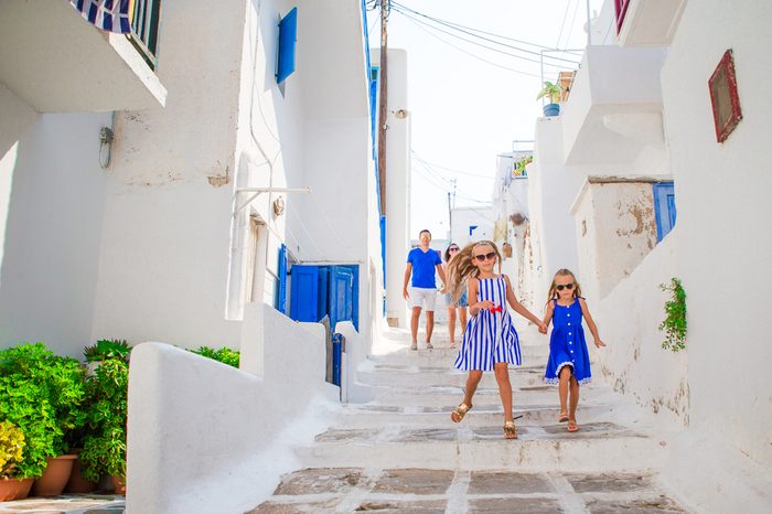Family vacation in Europe. Father and kids at narrow street on Mykonos Island, in Greece