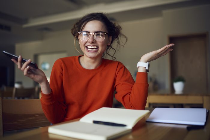 Portrait of cheerful female student laughing sitting in library satisfied with completing coursework making creative solution, smiling hipster girl received message with good advertising offer