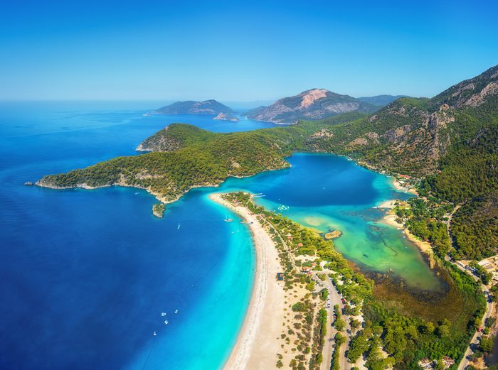 Amazing aerial view of Blue Lagoon in Oludeniz, Turkey. Summer landscape with mountains, green forest, azure water, sandy beach and blue sky in bright sunny day. Travel background. Top view. Nature
