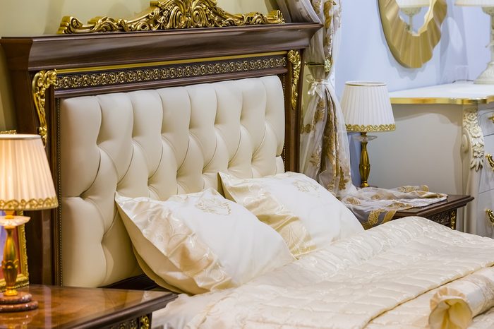 Luxury white bedroom in antique style with rich decor and bedside lamps