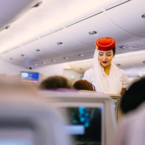 Dubai, UAE - JUNE 09, 2017: Emirates Airbus A380 economic class seats. In-flight entertainment system. Emirates cabin crew member, flight attendant. Airline food, dining, meals.