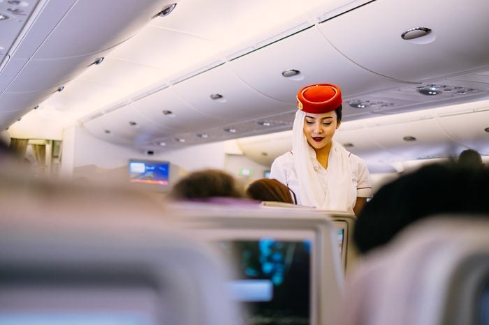 Dubai, UAE - JUNE 09, 2017: Emirates Airbus A380 economic class seats. In-flight entertainment system. Emirates cabin crew member, flight attendant. Airline food, dining, meals.