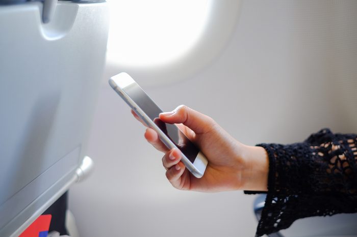 close up soft focus on businesswoman hand holding smartphone for checking work or playing in the aircraft,business travel concept