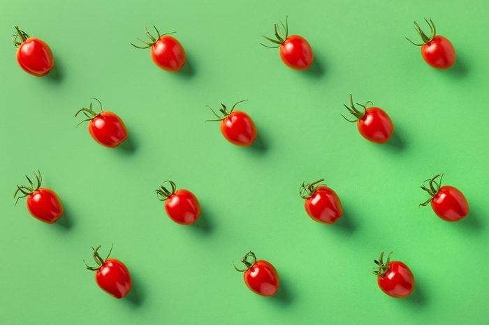 Colorful pattern of red tomatos on green background. From top view