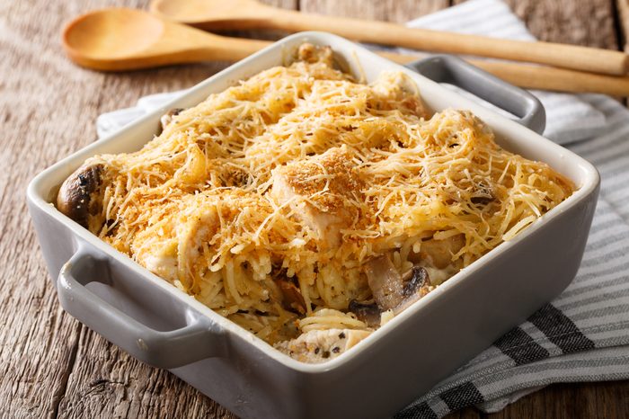 American tetrazzini with spaghetti, mushrooms, cheese, chicken close-up in a plate for baking on a table. horizontal