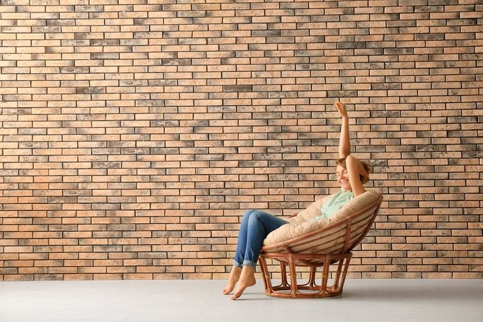 Young woman resting in lounge chair near brick wall