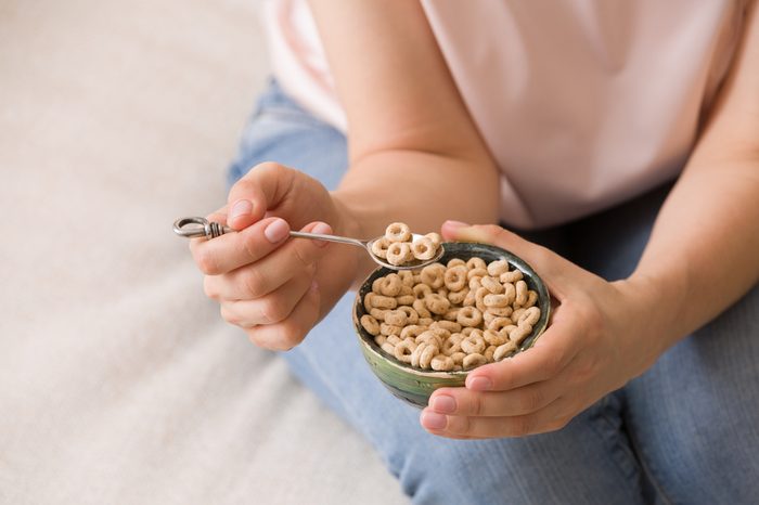 Top view on woman's hands holding bowl with organic whole wheat cereal. Healthy food and eating. Healthy breakfast or snack.