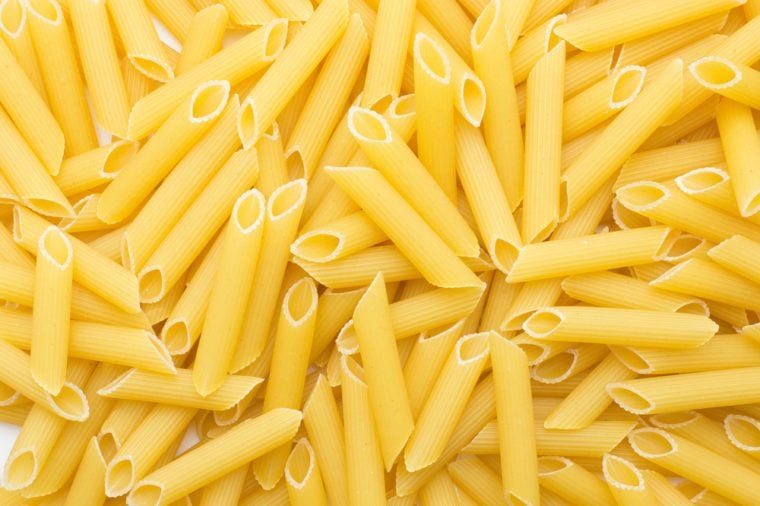 Penne rigate background top view a lot of dry raw pasta pieces