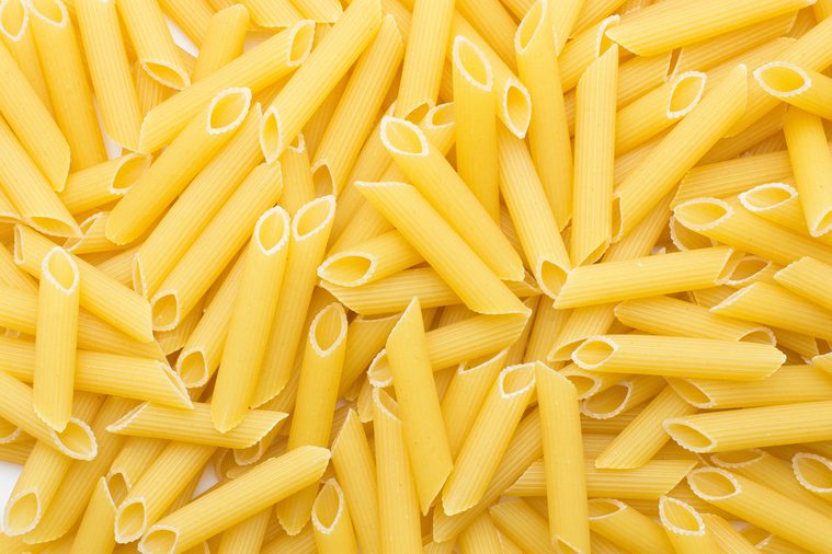 Penne rigate background top view a lot of dry raw pasta pieces