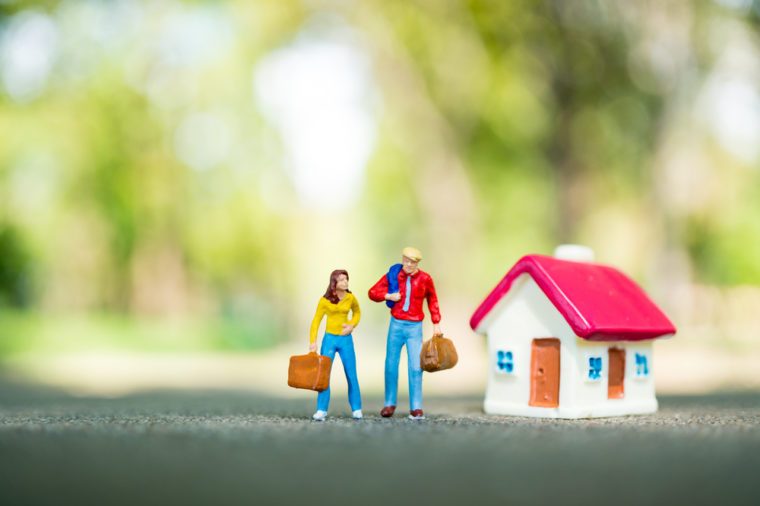 Miniature people, man and woman standing with mini house on green nature background using as business, financial and family concept