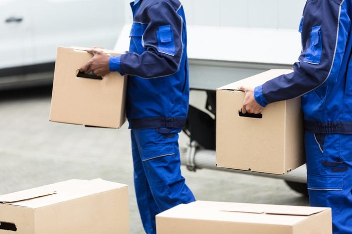 Close-up Of Two Delivery Men Holding The Cardboard Boxes
