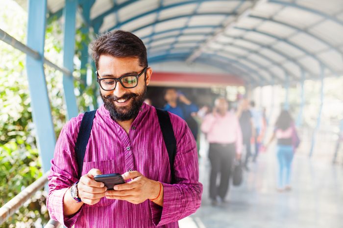 Bearded indian man on metro station using app in his smartphone 