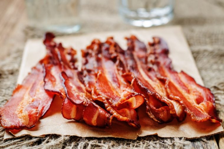 baked slices of bacon on a dark wooden background. toning. selective focus
