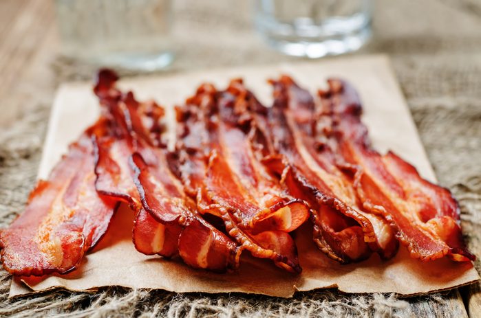 baked slices of bacon on a dark wooden background. toning. selective focus