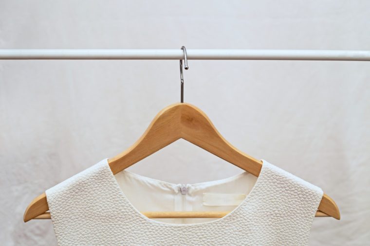 Light ladies sleeveless o-neck blouse on wooden hangers on light background