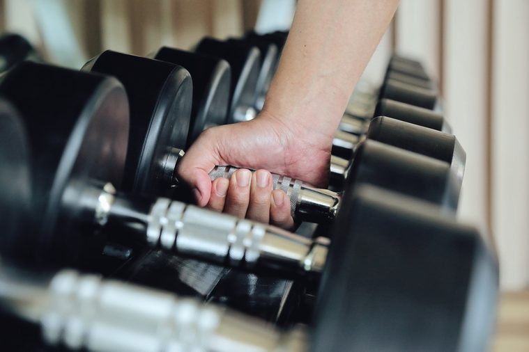 Hand holding dumbbell in the gym bodybuilding, Close up. Muscular arm in the fitness center. Training, sports,The concept of a healthy lifestyle and fitness. article about fitness and sports.