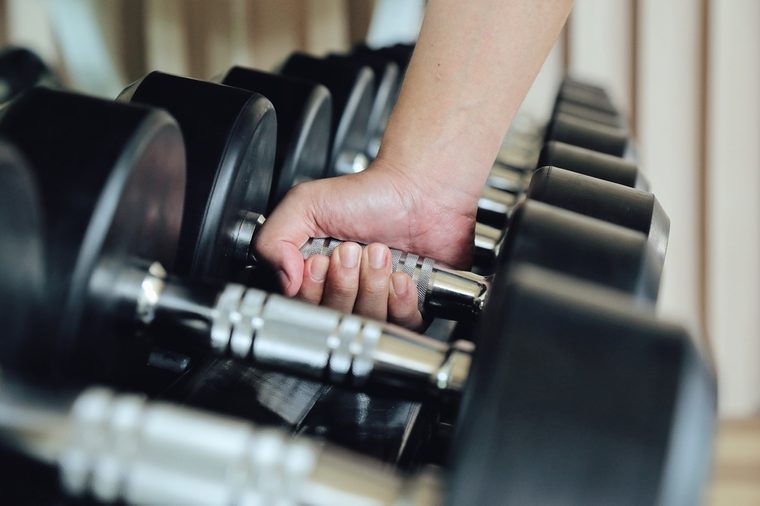 Hand holding dumbbell in the gym bodybuilding, Close up. Muscular arm in the fitness center. Training, sports,The concept of a healthy lifestyle and fitness. article about fitness and sports.