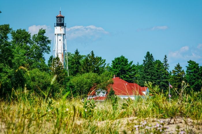 A Wisconsin lighthouse rises out of the forest looking over Lake Michigan.