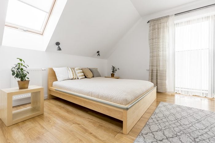 Bright attic bedroom with wood double bed and floor panels