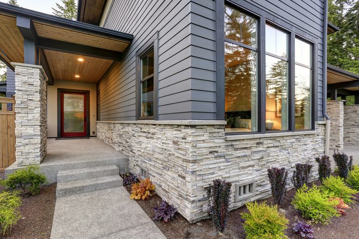 Luxurious new home with curb appeal. Trendy grey two-story exterior in Bellevue with large picture windows, stone siding, covered porch and concrete pathway. Northwest, USA