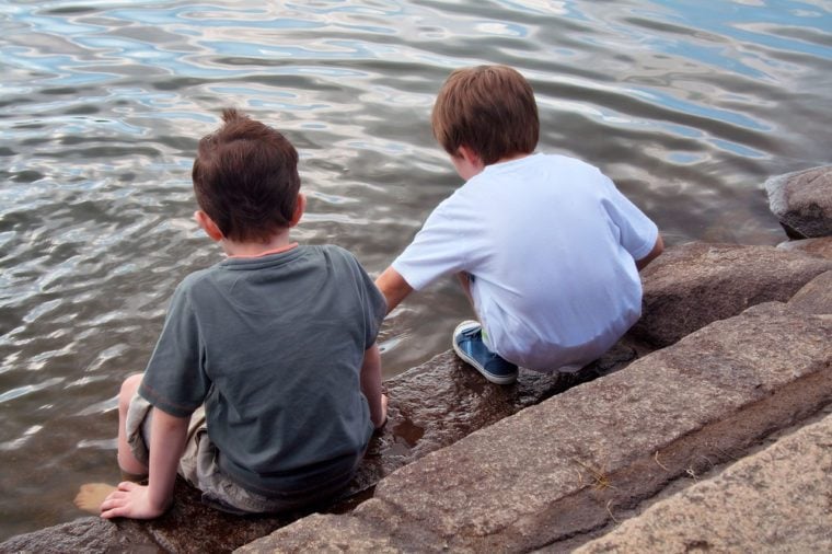 Young boys play beside lake