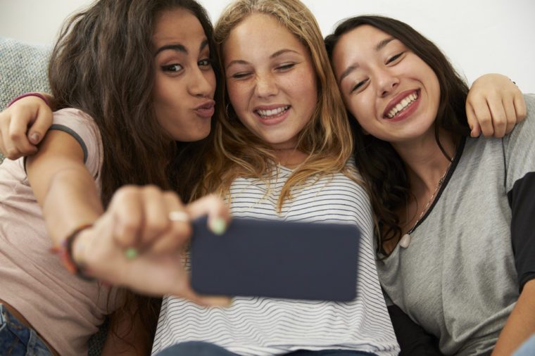 Three teenage girls taking selfie at home, focus on girls