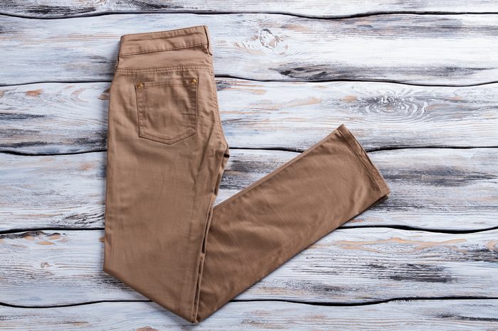 Woman's brown casual pants. Brown trousers on wooden background. Pants made of natural material. New item at low price.