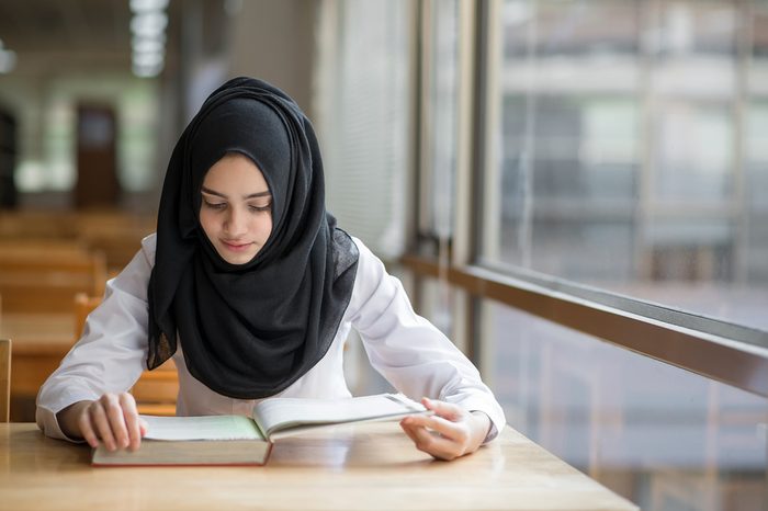 Muslim girl student studying at the library.