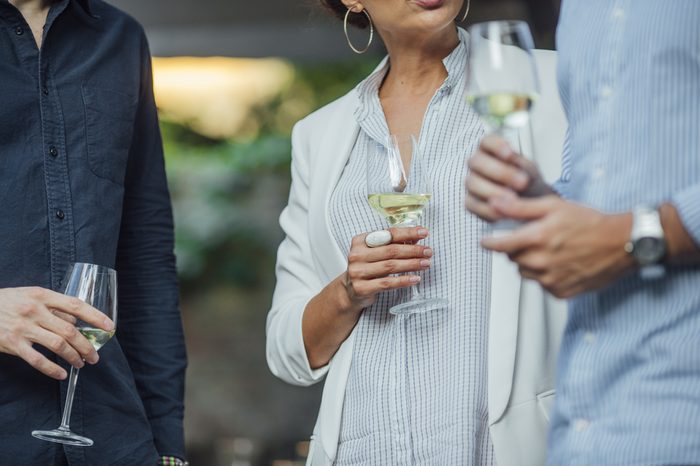 Cropped unrecognisable men and woman holding glasses of white wine and standing outdoor.