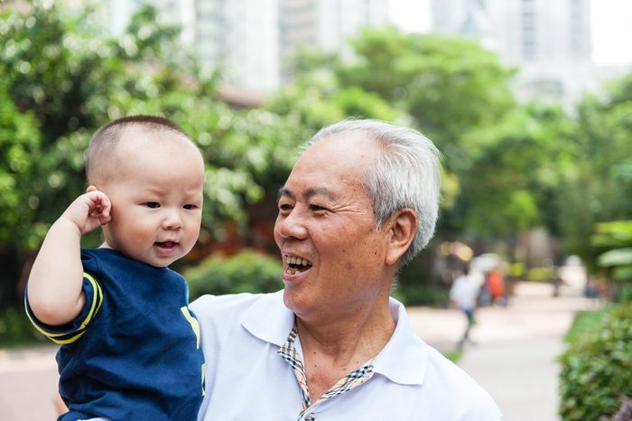 Asian grandfather holding grandson and walking in the garden