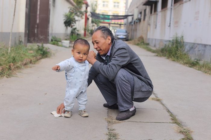 1 year old cute baby boy learning walk with grandpa, most old people in China are in charging of taking care of their grandchildren