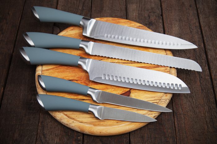 Set of five kitchen knives on wooden cutting board