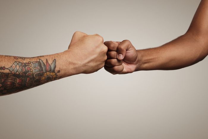 Friends do a fist bump close up isolated on white