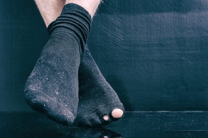 Legs bankrupt in black holey socks on a black background