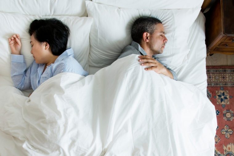 Interracial couple sleeping back to back on the bed