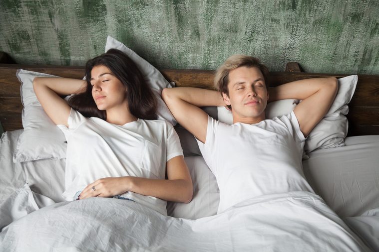 Young couple resting together with eyes closed sleeping well in comfortable bed before waking up in the morning, woman and man lying asleep in cozy bedroom at home, healthy good night sleep concept