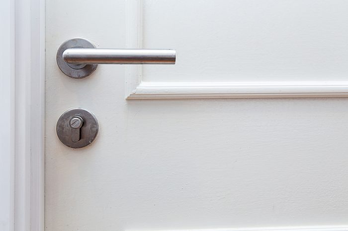 Metallic knob handle with hole key on white door. Closed up with copy space.