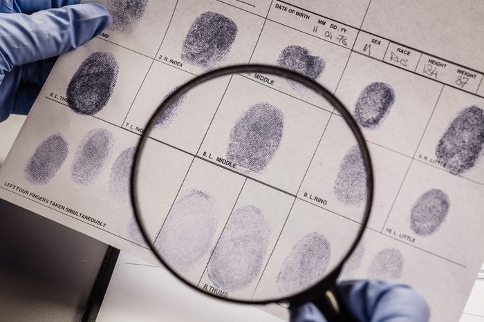 Criminology expert through a magnifying glass looking at a fingerprint