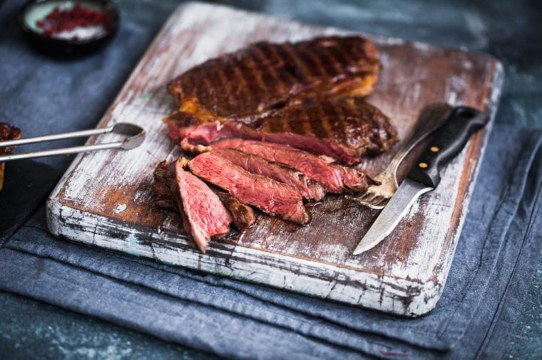 Grilled ribeye beef steak on a cutting board. Hot medium rare beef steak sliced.