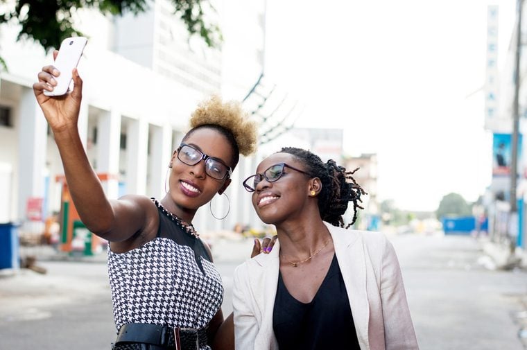 Two happy businesswomen taking selfie by smart phone outside