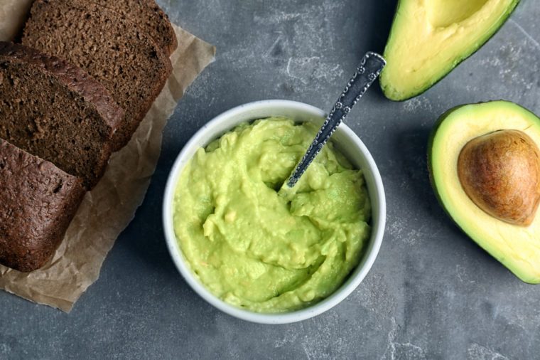 Flat lay composition with guacamole, bread and ripe avocado on grey background