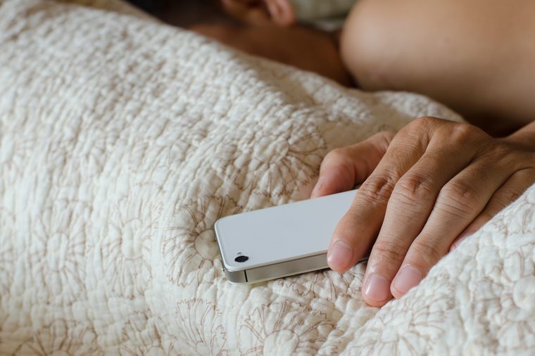 Man sleeping in bed and holding a mobile phone. Concept photo of smart phone addiction